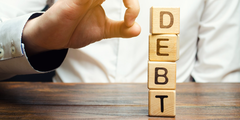 Businessman removes wooden blocks with the word Debt. Reduction or restructuring of debt. Bankruptcy announcement. Refusal to pay debts or loans and invalidate them. Debts service relief